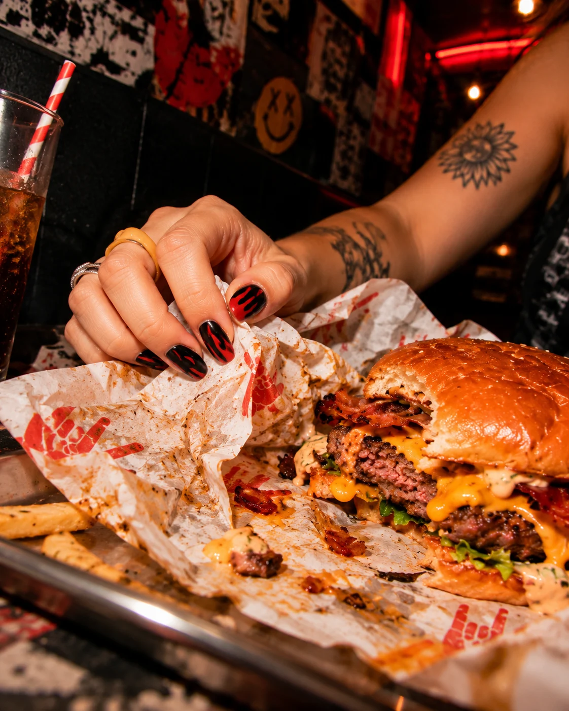 Detalle de la mano, el envoltorio y la hamburguesa