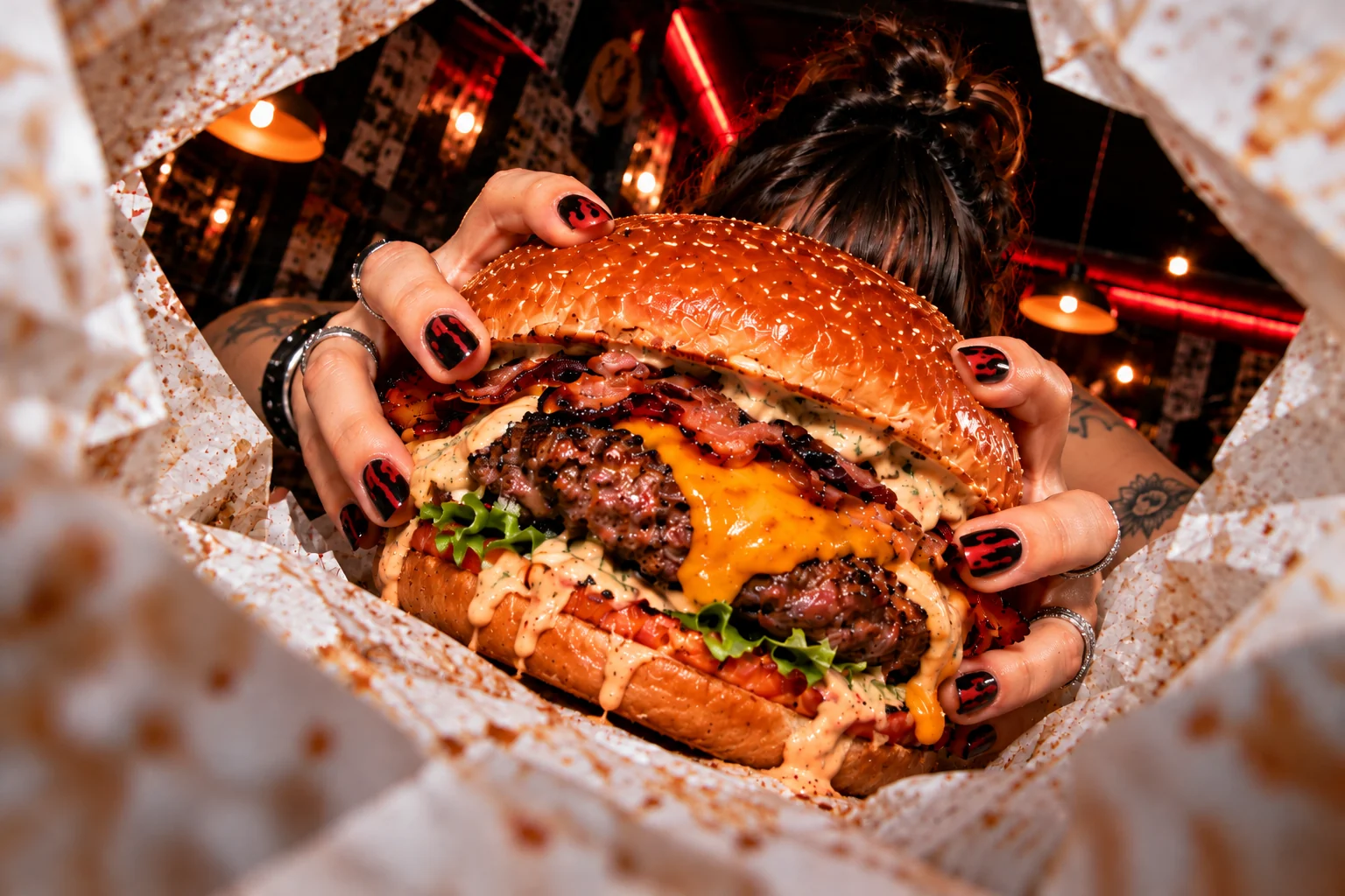 Hamburguesa vista desde su envoltorio; unas manos la sujetan y ocultan el rostro